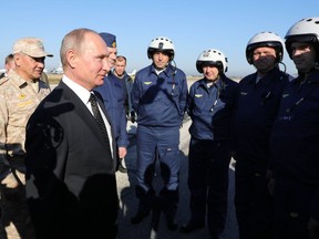 Russian President Vladimir Putin, 2nd left, and Defence Minister Sergei Shoigu, left, chat with Russian military pilots at the Hemeimeem air base in Syria, on Monday, Dec. 11, 2017. Declaring a victory in Syria, Putin on Monday visited a Russian military air base in the country and announced a partial pullout of Russian forces from the Mideast nation.