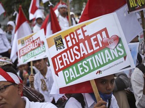 Muslim men hold posters during a rally against President Donald Trump's decision to recognize Jerusalem as Israel's capital outside the U.S. Embassy in Jakarta, Indonesia, Sunday, Dec. 10, 2017. Hundreds of people across the most populous Muslim country staged protests Friday against Trump administration's policy shift on the contested city.