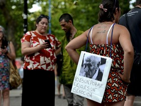 A woman stands with a picture of former police officer Miguel Etchecolatz that reads in Spanish, "He is not a poor man, he is a genocide" during a protest in Mar del Plata, Argentina, Friday, Dec. 29, 2017. Etchecolatz was sentenced to life in prison for crimes against humanity during Argentina last dictatorship but a court in Argentina has granted him house arrest Wednesday, due to health problems.