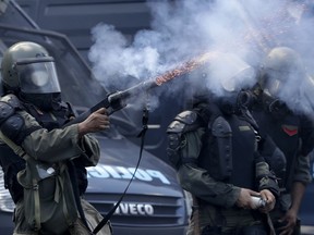 Police fires tear gas at stick-wielding protesters who hauled rocks and torched several garbage bins outside Argentina's Congress building and in nearby streets, in Buenos Aires, Argentina, Thursday, Dec. 14, 2017. Argentine police clashed Thursday with demonstrators protesting reforms to the retirement and pension system.
