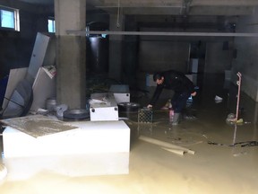 A man tries to clean his flooded shop after heavy rainfalls in Tirana, Friday, Dec. 1, 2017. A power company worker died and three others were injured Thursday after torrential rain in Albania flooded agricultural land, damaged roads and left tens of thousands of people without electricity, authorities said. (AP Photo/Hektor Pustina)