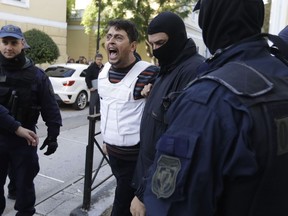 A Turkish man, no name available, escorted by anti-terror police shouts slogans as he arrives at a court to face terrorism charges in Athens, Monday, Dec. 4, 2017.  Nine suspected militants from Turkey, were arrested Tuesday Nov. 28, during a series of raids in Athens which according to police uncovered munition material, ahead of a visit by Turkish President Recep Tayyip Erdogan.
