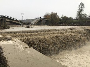 Local residents inspect a collapsed bridge at the entrance of their village Mamuras, northern Albania, Friday, Dec. 1, 2017. At least one person has died during heavy rainfall that flooded many parts of Albania, paralyzing its ports and causing flights from its only international airport to be suspended, authorities said Friday.