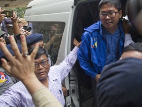 Reuters journalist Thet Oo Maung Maung, known as Wa Lone, exits a police van while his wife Pan Ei Mon waves upon his arrival at the township court for an appearance Wednesday, Dec. 27, 2017, outside Yangon, Myanmar. The court has extended the detention of the two Reuters journalists, Wan Lone and his colleague Kyaw Soe Oo, and set their trial date for Jan. 14 on charges of violating state secrets.