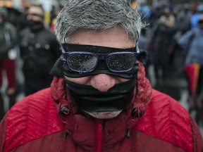 A man takes part in a flash mob in Bucharest, Romania, Sunday, Dec. 17, 2017. Protesters braved low temperatures and rain covering their mouths and eyes with black ribbons during a flash mob outside the government headquarters against planned modifications to Romanian justice legislation that critics say would render it less effective in punishing high-level corruption.
