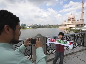 A muslim father taking picture of his son holding banner "Save Gaza" as they walks to Friday prayer in Putrajaya, Malaysia, Friday, Dec. 22, 2017. Malaysia prime minister Najib Razak led a huge rally to protest US move to recognize Jerusalem as Israel's capital.