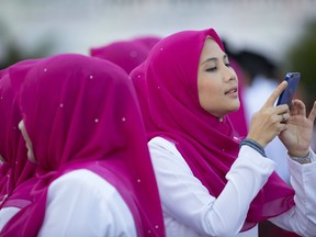 A member of United Malays National Organisation (UMNO) party takes a picture with her cellphone before the opening ceremony of the party's general assembly in Kuala Lumpur, Malaysia, Thursday, Dec. 7, 2017. Malaysian Prime Minister Najib Razak is expected to rally for unity in the three days annual assembly ahead of the general elections which must be held by August 2018.