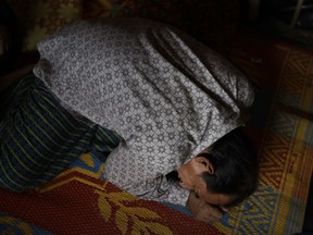 In this Saturday, Nov. 25, 2017, photo, Bodru Duza, 52, demonstrates how he hid in his house when members of Myanmar's military forces accused of massacring civilians in his village Maung Nu, in Myanmar's Rakhine State, during and interview with The Associated Press in his tent in Kutupalong refugee camp in Bangladesh. After the massacre, Duza lost track of his wife and children and fled to Bangladesh alone, assuming all of them had been killed. But in mid-November, they were reunited in a refugee camp in Bangladesh. More than 650,000 Rohingya Muslims have fled to Bangladesh from Myanmar since August, and many have brought with them stories of atrocities committed by security forces in Myanmar, including an Aug. 27 army massacre that reportedly took place in the village of Maung Nu.