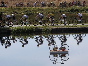 FILE - In this Wednesday, July 5, 2017 file photo Britain's Geraint Thomas, wearing the overall leader's yellow jersey, and new overall leader Britain's Chris Froome, left of Thomas, are reflected in a pond as they ride in the pack during the fifth stage of the Tour de France cycling race over 160.5 kilometers (99.7 miles) with start in Vittel and finish in La Planche des Belles Filles, France.