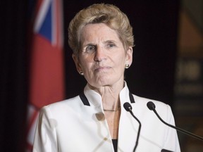 Ontario Premier Kathleen Wynne accused two of the children of Tim Hortons' billionaire co-founders, who are also franchise owners, of bullying their employees by reducing their benefits in response to the province's increased minimum wage.