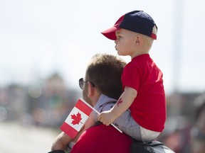 A child watches the Canada Day parade from his father's shoulders along Franklin Avenue in downtown Fort McMurray Alta. on Saturday July 1, 2017.