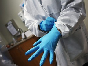 A dentist dons sterile gloves at a community health centre on March 27, 2012 in Aurora, Colorado.