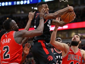 Delon Wright of the Toronto Raptors rebounds the ball between Jerian Grant and Nikola Mirotic  of the Bulls during the game Wednesday night at the United Center in Chicago.