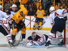 Goalie Cam Talbot of the Edmonton Oilers dives to cover a puck in the crease in front of Craig Smith of the Nashville Predators during the third period at Bridgestone Arena on Tuesday in Nashville, Tennessee.