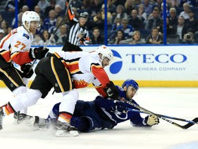 Cedric Paquette of the Tampa Bay Lightning fights for the puck with Mark Giordano and Dougie Hamilton, left, of the Calgary Flames at Amalie Arena on Thursday in Tampa, Florida.