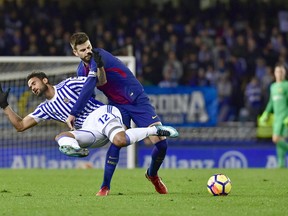 FC Barcelona's Gerard Pique, tackles Real Sociedad's Willian Jose during the Spanish La Liga soccer match between Barcelona and Real Sociedad, at Anoeta stadium, in San Sebastian, northern Spain, Sunday, Jan.14, 2018.