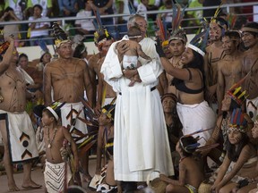 A priest holds a baby as clergy and indigenous people wait for the arrival of Pope Francis in Puerto Maldonado, Madre de Dios province, Peru, Friday, Jan. 19, 2018. Francis is expected to meet with several thousand indigenous people gathering in a coliseum in Puerto Maldonado, the city considered a gateway to the Amazon, in the first full day of the pontiff's visit to Peru.