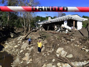 This file photo taken on January 12, 2018 shows rescue workers walking amid the debris of damaged property from mudflows carrying boulders, rocks and uprooted trees in Montecito, California.