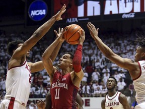 Oklahoma guard Trae Young (11) puts up a shot between Alabama forward Braxton Key (25) and guard Dazon Ingram (12) during the first half of an NCAA college basketball game, Saturday, Jan. 27, 2018, in Tuscaloosa, Ala.