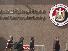 People walk in front of the National Election Authority, which is in charge of supervising the 2018 presidential election, in Cairo, Egypt, Monday, Jan. 22, 2018. Egypt will hold its presidential election over three days in March with President Abdel-Fattah el-Sissi virtually guaranteed to win a second four-year term amid a heavy clampdown on dissent.