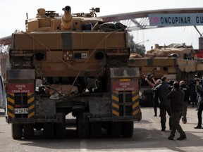 Turkish army tanks cross the Oncupinar border gate to enter Syria, in Kilis, Turkey, Saturday, Jan. 27, 2018. Turkey continued to reinforce its military presence in Syria Saturday, a day after the country's president vowed to expand Ankara's operation in a Kurdish enclave in northern Syria eastward toward the Iraqi border, trucks carried tanks and other armored vehicles into Syria.