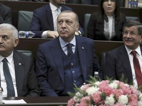 Turkey's President Recep Tayyip Erdogan, center, Prime Minister Binali Yildirim, left, and former Prime Minister Ahmet Davutoglu look toward the party members at the parliament in Ankara, Turkey, Tuesday, Jan. 30, 2018. Turkish troops and allied Syrian opposition fighters have cleared two villages in a northern Syrian enclave of Syrian Kurdish fighters which Turkey considers to be terrorists. Erdogan said Tuesday that Turkish troops, who had managed to capture the strategic Bursayah hill, northeast of Afrin town, on Sunday, were now attempting to take control of nearby hills and mountains.