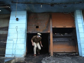 An Indian police officer exits the burnt restaurant in Kalasipalyam district, a busy and congested area in Bangalore, India, Monday, Jan. 8, 2018. A fire in the restaurant early Monday killed workers who were sleeping inside the building in the southern Indian city of Bangalore, police said.