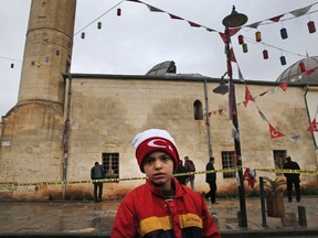 A boy stands in front of Calik mosque damaged on a rocket attack Wednesday night, in the town of Kilis, Turkey, near the border with Syria, Thursday, Jan. 25, 2018, after two rockets fired from inside Syria wounded at least 13 people when they hit a house and the mosque during evening prayers. This is the latest in a series of rocket attacks against the Turkish border town since Ankara launched a military offensive into Afrin.