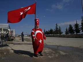 Isikli Tosun Baba, 60, holding and dressed in Turkish flags shows his support of the Turkish forces' offensive, in the Kurdish-controlled enclave of Afrin, Syria, at the Oncupinar border crossing with Syria, known as Bab al Salameh in Arabic, in the outskirts of the town of Kilis, Sunday, Jan. 28, 2018.