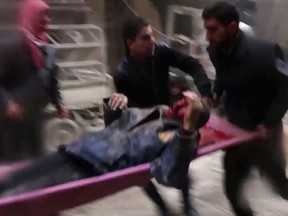 In this frame grab from video released Monday Jan. 1, 2018 by the Syrian Civil Defense group, known as the White Helmets, Syrians carry an injured man on a stretcher after an airstrike hit the Damascus suburb of Masraba, Syria. Opposition activists are reporting heavy clashes between government forces and insurgents east of Damascus, and at least a dozen airstrikes.