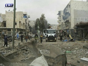 In this photo provided on Wednesday Jan. 3, 2018 by the Syrian anti-government activist group, Edlib Media Center, EMC, which has been authenticated based on its contents and other AP reporting, shows members of the Syrian civil defense known as the White Helmets, gathering at a street which was attacked by Russian airstrikes, in Maarat al-Nuaman town, southern Idlib province, Syria. Syrian government forces and allied militiamen are advancing on the largest remaining rebel-held territory in the country's north, forcing thousands of civilians to flee toward the border with Turkey amid a crushing offensive just as the cold winter weather sets in.