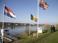 In this photo taken on Monday, Dec. 14, 2015, people walk past Dutch and Belgian flags on the waterfront in Eijsden, Netherlands.