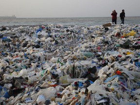 In this Monday, Jan. 22, 2018, photo, a man takes photos of piles of garbage washed on shore after an extended storm battered the Mediterranean country at the Zouq Mosbeh costal town, north of Beirut, Lebanon. Environmentalists say a winter storm has pushed a wave of trash onto the Lebanese shore outside Beirut, stirring outrage over a waste management crisis that has choked the country since 2015.