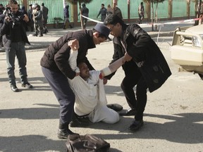 A wounded man is assisted at the site of an explosion in downtown Kabul, Afghanistan, Saturday, Jan. 27, 2018. The Interior Ministry says a suicide car bomb attack in Kabul leaves dozens wounded.