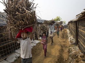 FILE - In this Monday, Jan. 15, 2018, file photo, a Rohingya family carry firewood on their head as they walk towards their tent at Balukhali refugee camp 50 kilometers (32 miles) from Cox's Bazar, Bangladesh. Bangladesh officials say they have agreed with Myanmar that they will try to complete the repatriation of Rohingya Muslim refugees who fled from violence in Myanmar within two years.