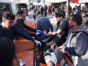 People help carry an injured man to the hospital following a suicide attack in Kabul, Afghanistan, Saturday Jan. 27, 2018. The Public Health Ministry says over a dozen were killed, and over 100 wounded ina suicide car bombing in downtown Kabul.