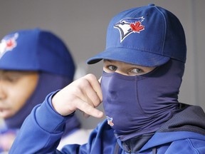 In this April 15, 2014 file photo, Toronto Blue Jays third baseman Brett Lawrie pretends to talk on the phone as he sits bundled up during a game against the Minnesota Twins.