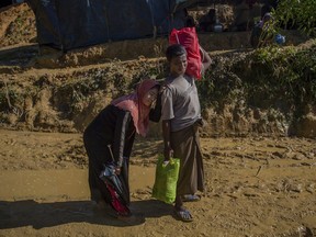 FILE- In this Sept. 24, 2017, file photo, nine months pregnant Rohingya Muslim woman, Hajira Begum in pain leans her head on the shoulder of her husband Mohammad Sayeed as they walk towards hospital at Kutupalong refugee camp, Bangladesh. An international aid agency projects that 48,000 babies will be born in overcrowded refugee camps this year for Rohingya who have fled to Bangladesh from neighboring Myanmar. Save the Children warned in a report released Friday, Jan. 5, 2018, that the newborns will be at an increased risk of disease and malnutrition, and therefore of dying before the age of five.