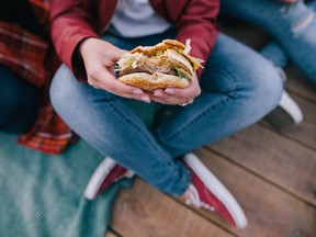 Tasty burger in woman's hands. Takeaway junk food