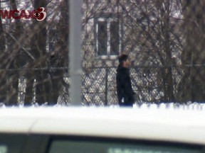 A man walks with a handgun on the grounds of Montpelier High School, Tuesday Jan. 18, 2018, in Montpelier, Vt. Police said the man, who tried to rob the Vermont State Employees Credit Union across the street from the school, was shot and killed by police on the school grounds. (WCAX-TV via AP)