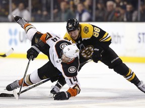Anaheim Ducks' Adam Henrique (14) is sent to the ice by Boston Bruins' David Pastrnak during the third period of Anaheim's 3-1 win in an NHL hockey game in Boston on Tuesday, Jan. 30, 2018.
