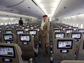 FILE - In this March 12, 2014 file photo, a stewardess stands inside an Emirates A380 aircraft, the world's largest passenger airline, during the fourth Indian Aviation show at Begumpet airport in Hyderabad, India. Emirates airline said in a statement Thursday, Jan. 18, 2018, that they are purchasing 20 A380 aircraft with the option for 16 more in a deal worth $16 billion, throwing a lifeline to the European-made double-decker jumbo jets.