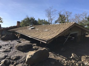 In this photo provided by Santa Barbara County Fire Department, mudflow, boulders, and debris from heavy rain runoff from early Tuesday reached the roof of a single story home in Montecito, Calif., on Wednesday, Jan. 10, 2018.