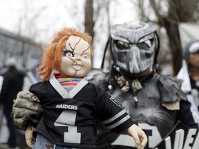 A fans holds a doll outside of the Oakland Raiders team headquarters before an NFL football press conference to announce John Gruden as the team's new coach Tuesday, Jan. 9, 2018, in Alameda, Calif.