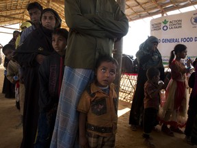 In this Sunday, Jan. 21, 2018, photo, a Rohingya refugee boy who is among those being relocated from a camp near the Bangladesh Myanmar border wait to receive a food card on reaching at the Balukhali refugee camp 50 kilometers (31 miles) from, Cox's Bazar, Bangladesh. With the first repatriations of Rohingya refugees back to Myanmar just days away, and more than 1 million living in refugee camps in Bangladesh, international aid workers, local officials and the refugees say preparations have barely begun  and most refugees would rather contend with the squalor of the camps than the dangers they could face if they return home. It's unclear if more than a handful of Rohingya will even be willing to go home.