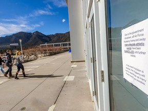 People walk towards the Cadet Field House as a sign reads that the Air Force Academy has canceled all athletic events on Saturday Jan. 20, 2018 at the U.S. Air Force Academy in Colorado Springs, Colo. Hours after the partial shutdown took effect, the academy said both home and away events have been postponed. The academy's online sports calendar lists seven competitions that had been set for Saturday: men's and women's basketball games at Fresno State, men's and women's swimming at UNLV, men's hockey against Sacred Heart at the academy and men's gymnastics against Oklahoma at the academy.