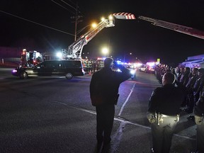 A flag hung down from Truck 53 and Tower 51 to form the archway as Brighton, Colo., police officers stood at attention and saluted as the hearse carrying Adams County Sheriff's Office Deputy Heath Gumm arrives at the Adams county coroner on Thursday, Jan. 25, 2018, in Brighton. Gumm was killed Wednesday night responding to a call in a residential area north of downtown Denver, the sheriff's office said.
