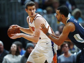 Phoenix Suns forward Dragan Bender, left, looks to pass the ball as Denver Nuggets forward Trey Lyles defends during the first half of an NBA basketball game Friday, Jan. 19, 2018, in Denver.