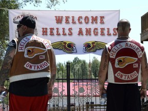 Members of the Hells Angels look on as their banner is raised outside the Hells Angels Nomads compound before the group's Canada Run event in Carlsbad Springs, Ont., near Ottawa, on Friday, July 22, 2016. A "prolific growth" in the presence of outlaw motorcycle gangs in the Halifax area has prompted an RCMP request for more front-line officers.