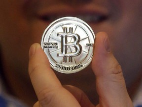 A man holds a 25 Bitcoin token in Sandy, Utah in an April 3, 2013 file photo. When most Canadians think of Drumheller, they conjure up images of dinosaur bones and ancient fossils. But entrepreneur Sean Clark's expedition in the northern Alberta town is focused on a very current obsession: Bitcoin.